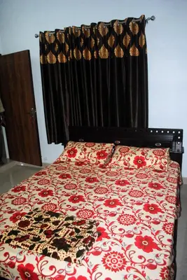a bedroom with a bed with a red and white comforter at NICE VILLA in Irimbranallūr