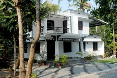 a white house with palm trees in front of it at NICE VILLA in Irimbranallūr