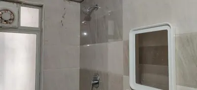 a shower with a glass door and a mirror at Garden House in Mysore