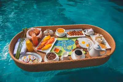 a tray of food on a table next to a swimming pool at Tuskers Hill by Poppys Anaikatti in Palghat