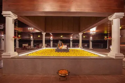 a large pool of yellow flowers in the middle of a building at Tuskers Hill by Poppys Anaikatti in Palghat