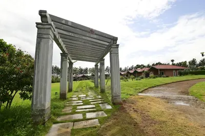 a stone pathway with a pergola next to a road at vihangama Home Stay in Chāmundi