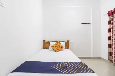 a bedroom with a bed with a blue and yellow blanket at SPOT ON Rohini Inn Kadampuzha in Malappuram