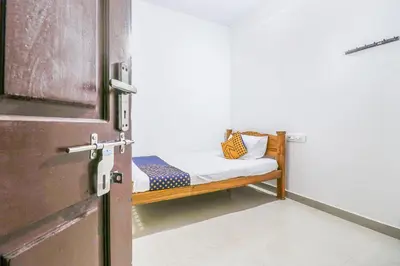 a small bed in a room next to a door at SPOT ON Rohini Inn Kadampuzha in Malappuram