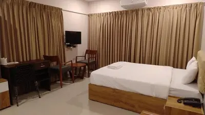 a hotel room with a bed and a desk and a television at Gateway Airport Hotel in Kannur