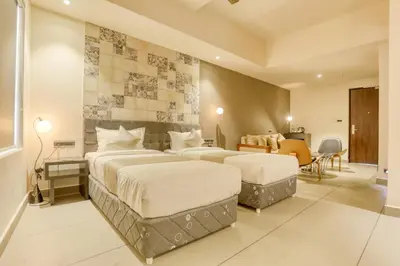 a hotel room with two beds and a table at AS AIRPORT Inn in Cochin