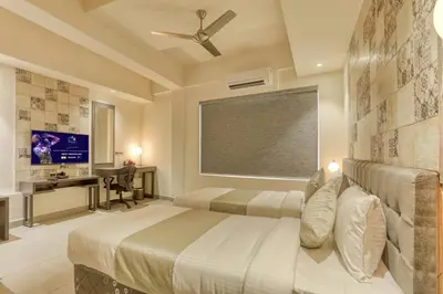 a bedroom with two beds and a desk and a television at AS AIRPORT Inn in Cochin