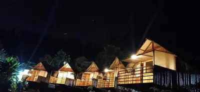 a row of huts lit up at night at Ibni Springs in Madikeri