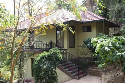 a small yellow house with stairs leading up to it at Serene Woods in Madikeri