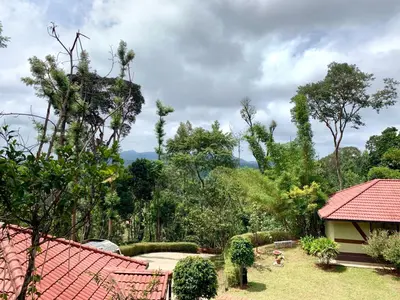 a garden with a red roof and trees at Serene Woods in Madikeri