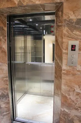 an elevator in a building with a glass door at Aura Residency in Trichūr