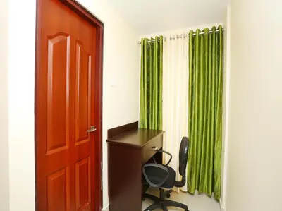 a room with a desk and a green curtain at Aura Residency in Trichūr