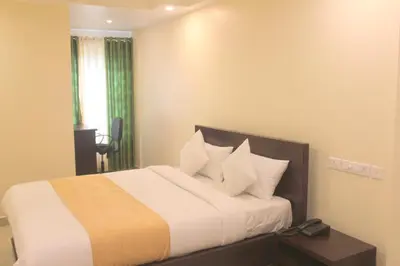 a bedroom with a bed with white sheets and pillows at Aura Residency in Trichūr