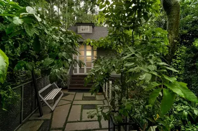 a garden with a bench and trees and a building at IRON BRIDGE COVE in Meppādi