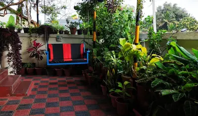 a patio with plants and a blue chair with a flag on it at Coorg peacock feathers home stay in Kushālnagar