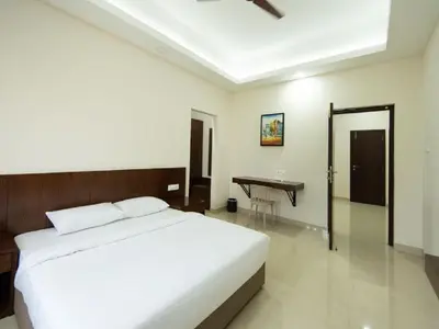 a bedroom with a bed and a desk in it at Mayfair Service Apartments in Pīlamedu