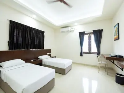 a bedroom with two beds and a desk and a table at Mayfair Service Apartments in Pīlamedu