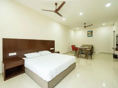 a bedroom with a bed and a table with chairs at Mayfair Service Apartments in Pīlamedu