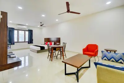 a living room with a bed and a table and chairs at Mayfair Service Apartments in Pīlamedu