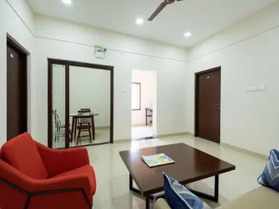 a living room with a red chair and a table at Mayfair Service Apartments in Pīlamedu