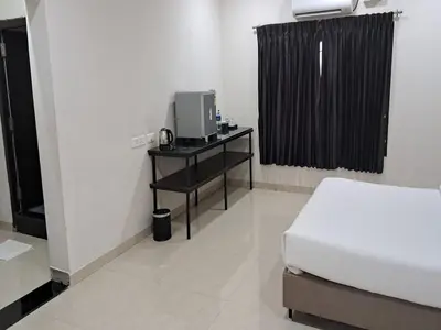 a bedroom with a bed and a television on a table at Mayfair Service Apartments in Pīlamedu