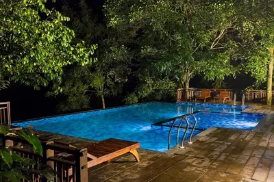 a swimming pool with a wooden bench next to it at Vythiri Mist Resort in Vythiri