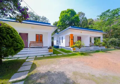 a white house with a blue roof at Vythiri Silver Mist Hilltop Villa By VOYE HOMES in Vythiri