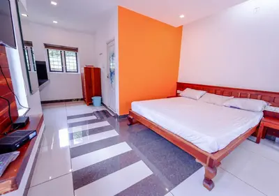 a bedroom with a bed and an orange wall at Vythiri Silver Mist Hilltop Villa By VOYE HOMES in Vythiri