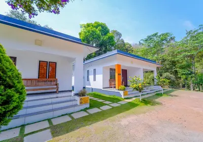 a small white house with a blue roof at Vythiri Silver Mist Hilltop Villa By VOYE HOMES in Vythiri