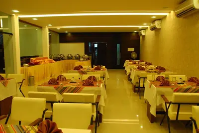 a dining room with white tables and chairs at Sayoojyam Residency in Palakkad