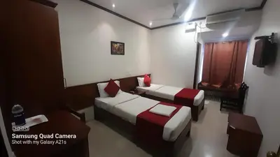 a room with two beds and a table and a window at Sayoojyam Residency in Palakkad
