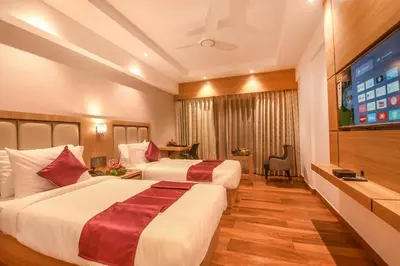 a hotel room with two beds and a flat screen tv at Emerald Clarks Inn Suites in Mysore