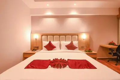 a bedroom with a large white bed with red pillows at Emerald Clarks Inn Suites in Mysore