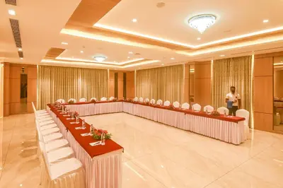 a room with rows of chairs and a man in a podium at Emerald Clarks Inn Suites in Mysore
