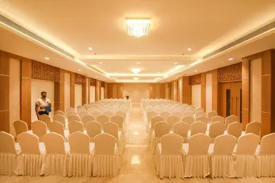 a man standing in a room with rows of chairs at Emerald Clarks Inn Suites in Mysore