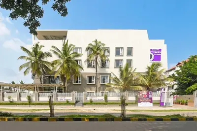 a white building with palm trees in front of it at Emerald Clarks Inn Suites in Mysore