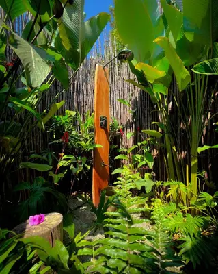 a wooden surfboard leaning against a fence in a garden at The Mudhouse Marayoor in Munnar