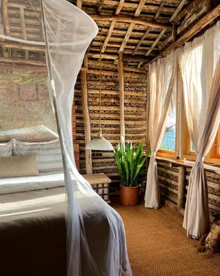 a bedroom with a bed with a mosquito net at The Mudhouse Marayoor in Munnar