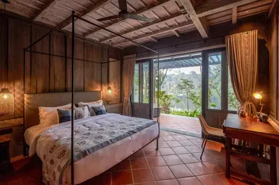 a bedroom with a bed in a room with a desk at Periyar River Lodge in Thattakād
