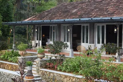 a house with a porch with potted plants at Periyar River Lodge in Thattakād