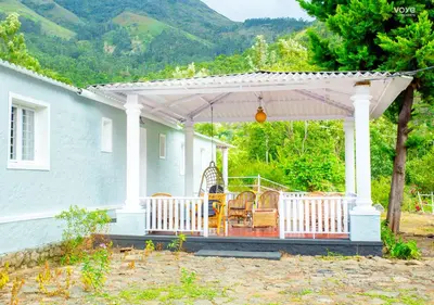 a pavilion with chairs and tables on a house at Moonlight Munnar Forest Bungalow with Private Waterfalls by VOYE HOMES in Kanthalloor