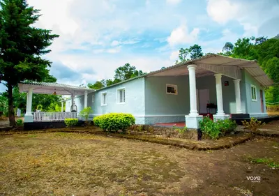a small blue house with a porch at Moonlight Munnar Forest Bungalow with Private Waterfalls by VOYE HOMES in Kanthalloor