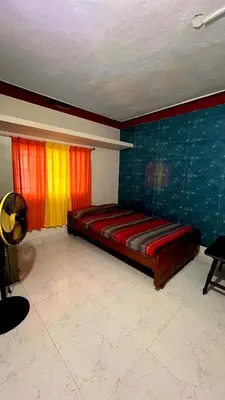 a bedroom with a bed and two windows with colorful curtains at Aiyappa Stays in Madikeri
