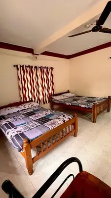 a bedroom with two beds and a ceiling fan at Aiyappa Stays in Madikeri