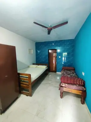 a bedroom with two beds and a ceiling fan at Aiyappa Stays in Madikeri