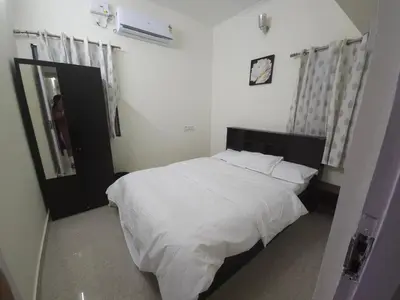 a bedroom with a white bed and a clock on the wall at Happy Home in Coimbatore