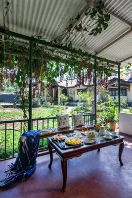 a table with food on it on a patio at SaffronStays Calamondinn Bungalow - 5BR Colonial Heritage Home within Coffee Plantation in Coorg in Gonikoppal