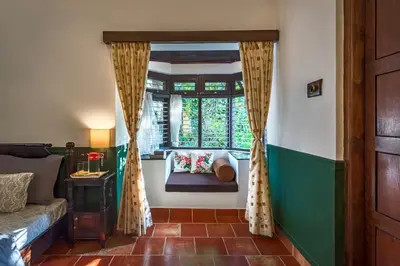 a room with a window and a couch in a room at SaffronStays Calamondinn Bungalow - 5BR Colonial Heritage Home within Coffee Plantation in Coorg in Gonikoppal