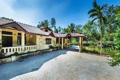 a house with a driveway in front of it at SaffronStays Calamondinn Bungalow - 5BR Colonial Heritage Home within Coffee Plantation in Coorg in Gonikoppal