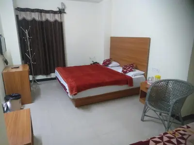 a bedroom with a bed and a chair in it at Red Star Holidays in Munnar